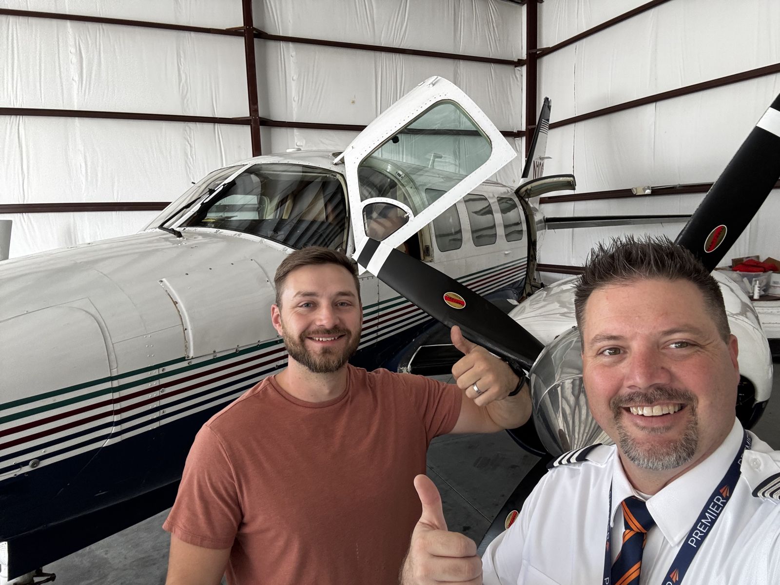 Thumbs up beside a twin in the hangar